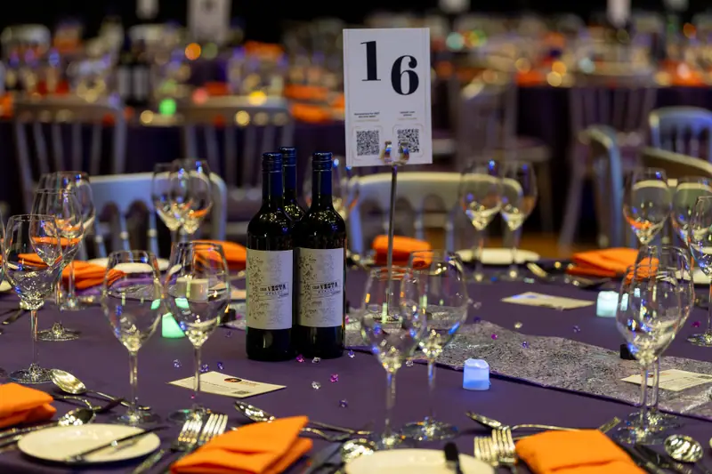 A dinner table laid for the evening, with wine, glassware and a table number.