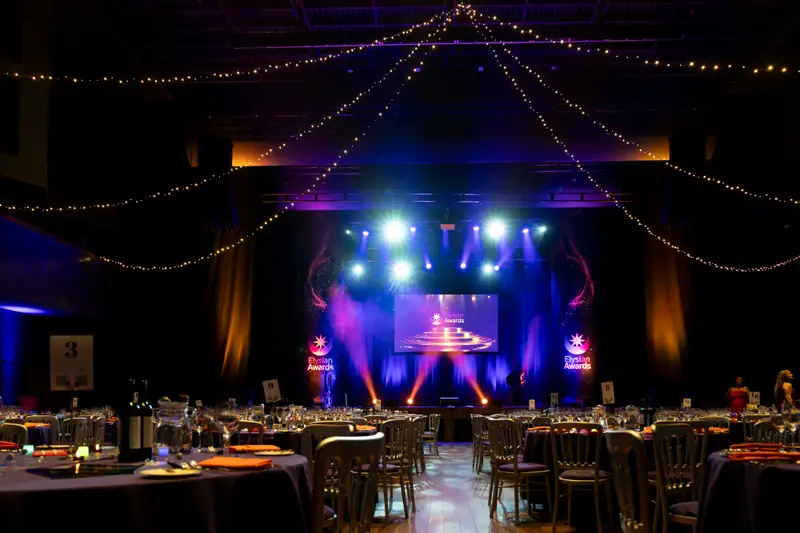The stage lit in purple and white at the far end of the empty ballroom.