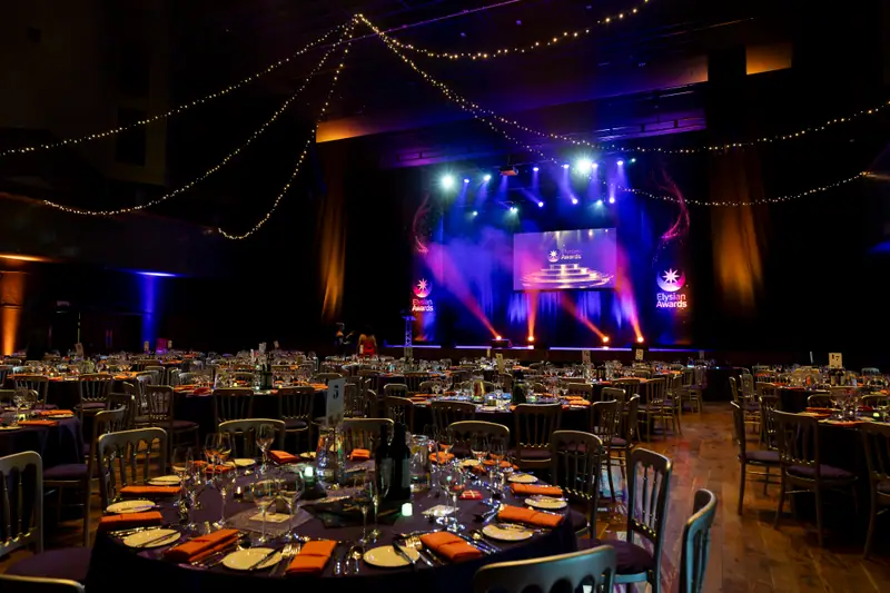 The room from the back, fairy lights overhead and the stage glowing in the distance.