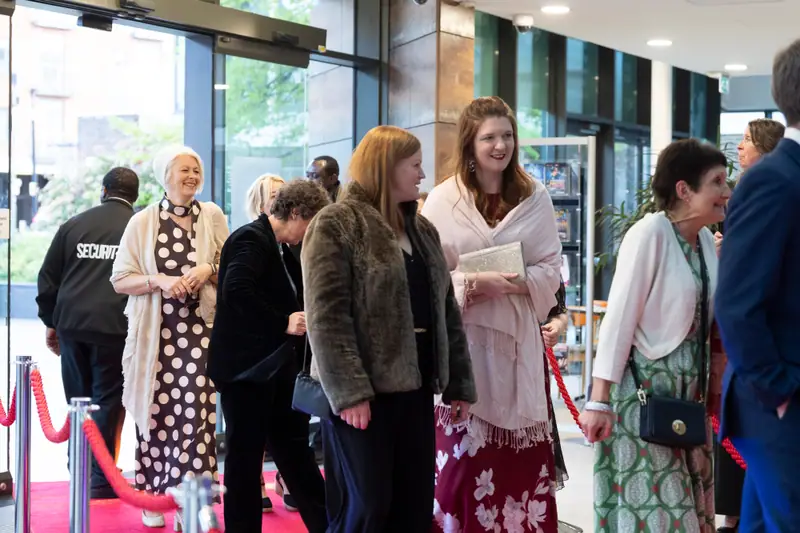 Guests queueing along the red rope at the entrance, waiting to walk the red carpet.