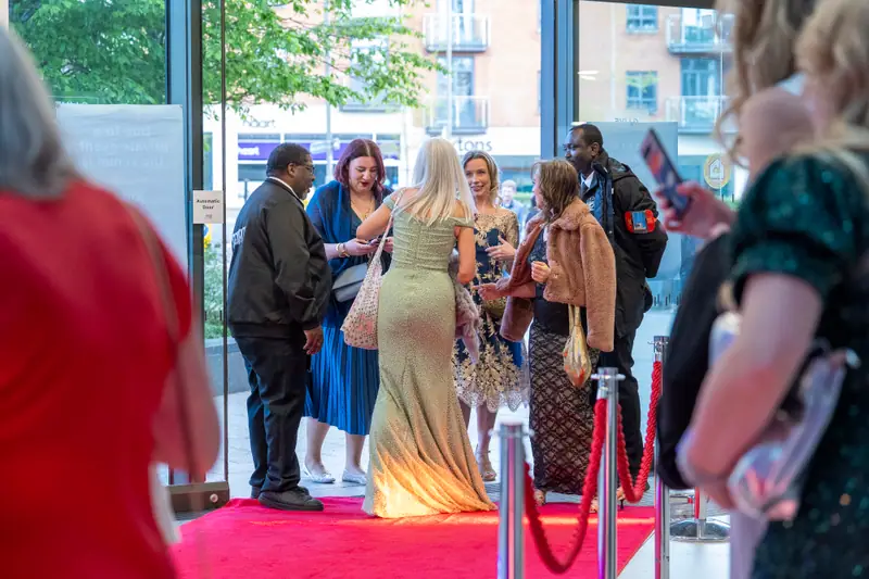 Guests gathering and greeting each other beside the red carpet as they arrive.