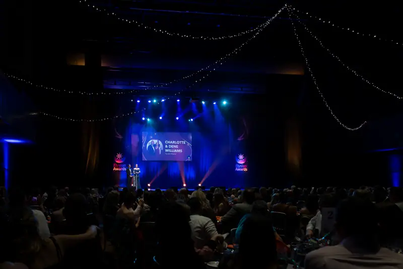 The audience in silhouette, facing the lit stage.