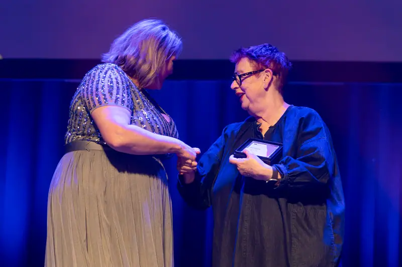 A winner shaking hands as she is presented with her award.