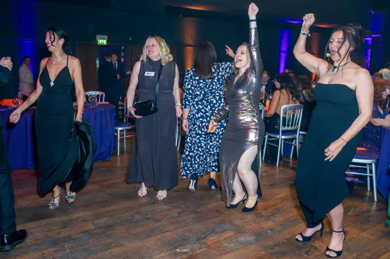 A group of guests dancing with their arms in the air.