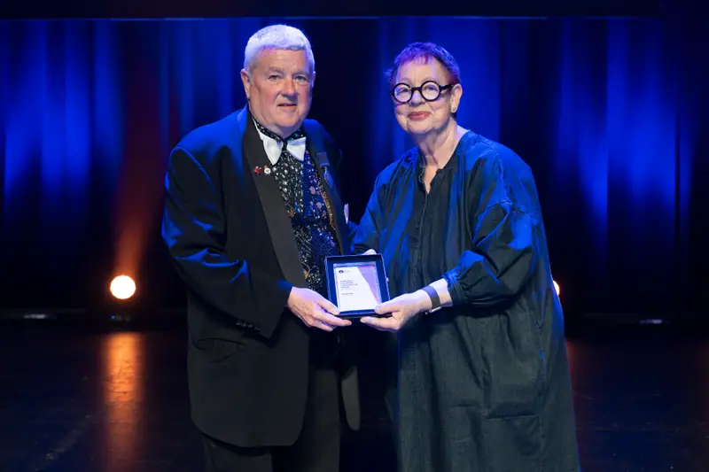 A winner and Jo Brand holding the award between them for the photographers.