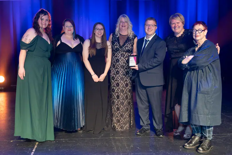 A winning team lined up on stage with their awards and certificates.