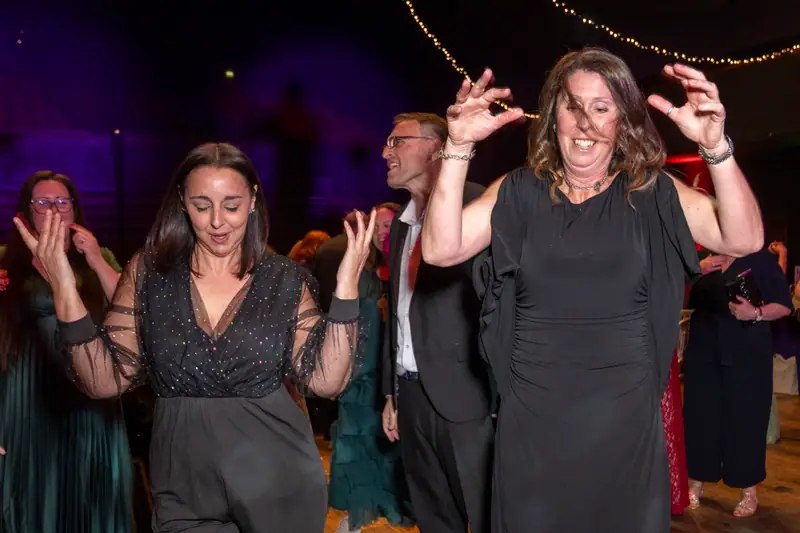 Guests laughing and dancing under the lights.
